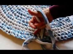 someone is crocheting the edge of a blue and white rug