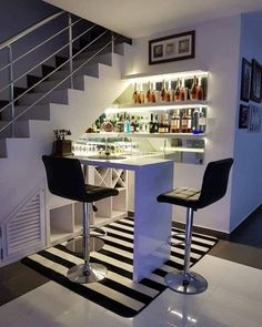 two bar stools sitting in front of a counter with liquor bottles on the shelves