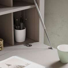 a white bowl sitting on top of a desk next to a cup and pen holder