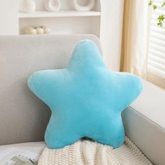 a blue star shaped pillow sitting on top of a white couch next to a window