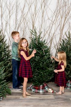 two young children standing in front of christmas trees