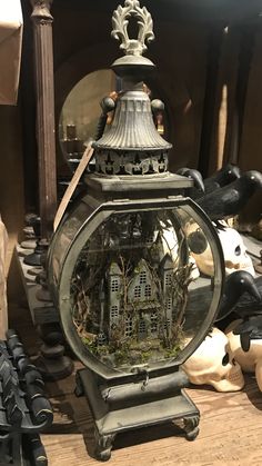 an old fashioned lantern with moss growing in it on a table next to other items