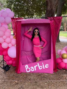 a woman in a pink dress and sunglasses posing for the camera with balloons surrounding her