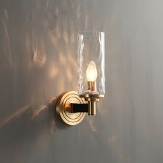 a light that is on the side of a wall next to a glass vase with something in it