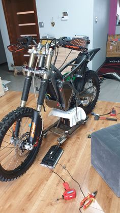 a motorbike is being worked on in a room with hard wood flooring