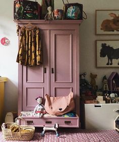 a pink armoire in a child's room with toys on the top shelf