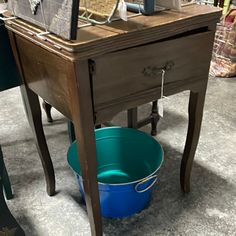 a blue bucket sitting on top of a wooden table next to a mirror and chair