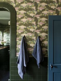 two blue towels hanging on the wall in front of a mirror