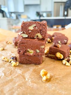 three pieces of brownie stacked on top of each other with nuts scattered around them