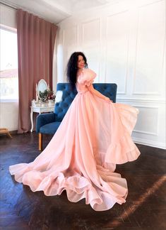 a woman in a pink dress standing on a blue chair