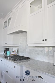 a kitchen with white cabinets and marble counter tops