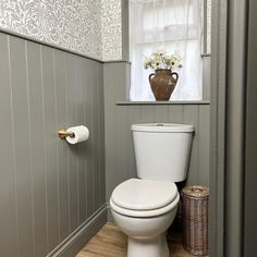 a white toilet sitting in a bathroom next to a window with flowers on the tank