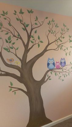 a tree with two owls sitting on it's branches and leaves painted on the wall