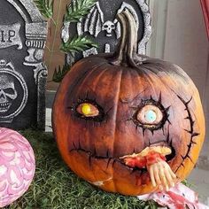 two carved pumpkins sitting on top of green grass next to tombstones with eyes