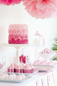 a table topped with lots of cake and cupcakes covered in pink frosting