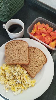 two pieces of bread sit on a plate with scrambled eggs and carrots next to a cup of coffee