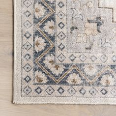 a white rug with blue and brown designs on it, sitting on a wooden floor