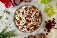 a bowl filled with chicken salad next to sliced onions and celery on a table