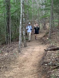 two people walking down a trail in the woods