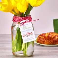 there is a jar with flowers in it next to a croissant