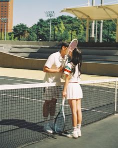 a man and woman kissing on the tennis court