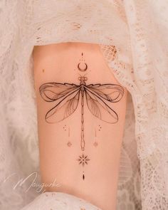 a woman's stomach with a dragonfly tattoo on her side and the moon behind it