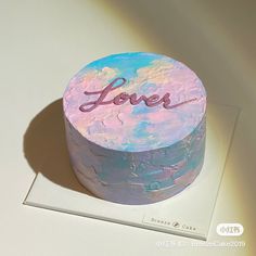 a colorful cake with the word love on it sitting on a white surface next to a card