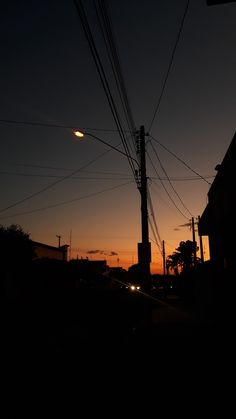 the sun is setting behind power lines and telephone poles in this dark cityscape