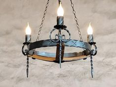 a chandelier made out of metal and wood with three lights hanging from it