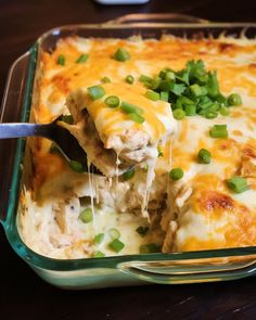 a casserole dish with meat, cheese and green onions being lifted from the casserole