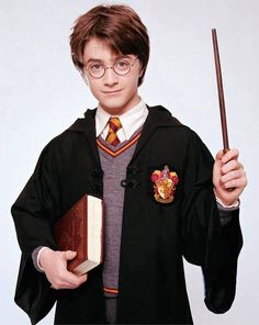 a young harry potter holding a book and wand