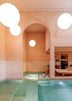 an indoor swimming pool with circular lights hanging from it's ceiling and tiled floor