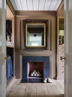 a room with a fireplace, mirror and shoes on the floor in front of it