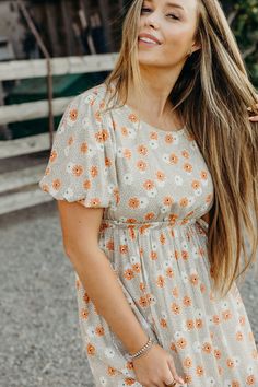 Get ready to stun in The Powell Dress, a western maxi featuring a natural sand color, double lace inset, and tiered skirt. The thick elastic waistband provides a comfortable fit while the open back concept adds a flirty touch. With a self tie ribbon at the back and neck, this lined dress also features a playful floral print. Haylee is wearing size small Beige Flowy Tiered Maxi Dress, Tiered Beige Maxi Dress For Day Out, Beige Summer Dress With Elastic Waistband, Cream Modest Maxi Dress For Summer, Modest Cream Maxi Dress For Summer, Beige Midi Dress With Elastic Waistband, Beige Maxi Dress With Smocked Back For Day Out, Modest Maxi Dress With Elastic Waistband For Summer, Beige Dress With Elastic Waistband