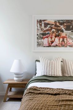 a bed with pillows and blankets in a bedroom next to a painting on the wall