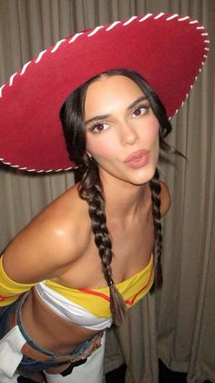 a woman wearing a red sombrero with braids on her head and yellow top