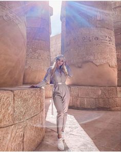 a woman standing in front of two large stone pillars with egyptian writing on the walls