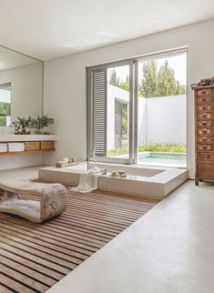 a bathroom with a tub, sink and large window overlooking the pool in front of it