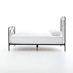 a metal bed frame with white sheets and pillows on it, against a white background