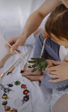 two people are painting on the ground with paintbrushes in their hands and one person is holding a plant