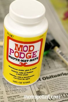 a bottle of mod podge matte - mate glue sitting on top of a newspaper