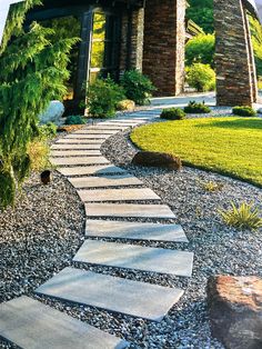 a stone path in the middle of a graveled area with trees and rocks around it