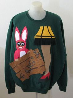 a green sweater with an image of a rabbit and a lamp on the front, sitting on a mannequin's head