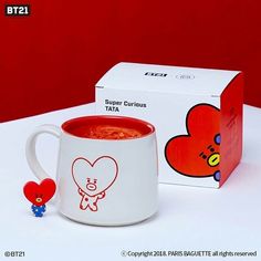 a red and white coffee mug next to a box with a heart on the side