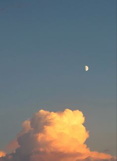 the moon is setting behind some clouds in the sky