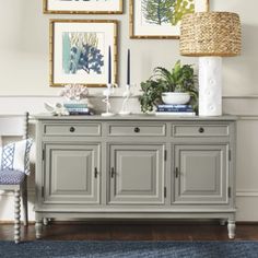 a gray buffet table with pictures on the wall above it and a blue rug underneath