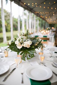 the table is set with white flowers and greenery for an elegant dinner or reception