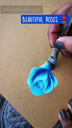 a person cutting paper with scissors and a blue rose