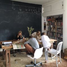 three people sitting at a table in front of a blackboard with writing on it