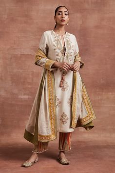 Beige kurta with gold dori, thread embroidery in floral placement pattern. Paired with mustard velvet border embroidered Pakistani salwar and dupatta. - Aza Fashions Chanderi Dupatta With Gold Embroidery, Traditional Raw Silk Dupatta With Gold Embroidery, Raw Silk Dupatta With Gold Embroidery, Elegant Anarkali Set With Gold Embroidery, Gold Embroidered Straight Kurta Set In Raw Silk, Gold Embroidered Raw Silk Straight Kurta Set, Transitional Raw Silk Salwar Kameez With Gold Embroidery, Gold Traditional Wear Straight Kurta With Floral Embroidery, Anarkali Sets With Gold Embroidery For Transitional Season